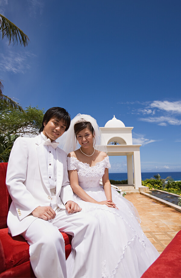 海边坐在一起面带微笑的新郎新娘图片图片
