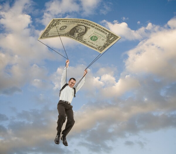 男人乘着大型钞票图案降落伞高清大图图片
