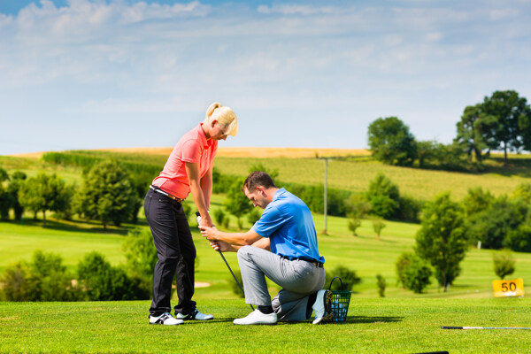 草地外国男人教外国女人打高尔夫球图片