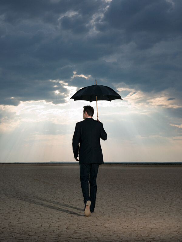 打着雨伞走在旱地里的外国男人图片