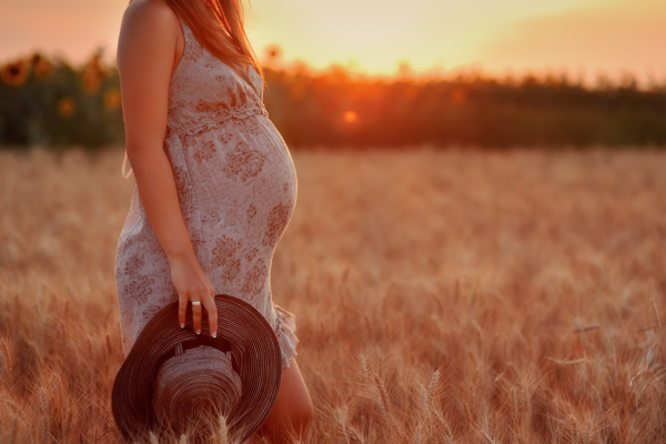 夕阳下走在草地上的孕妇图片