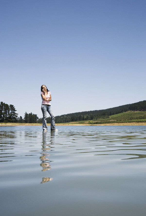 站立在水面打电话的女人图片
