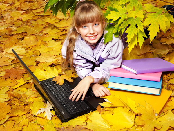 趴在枫叶地上玩电脑的女孩图片