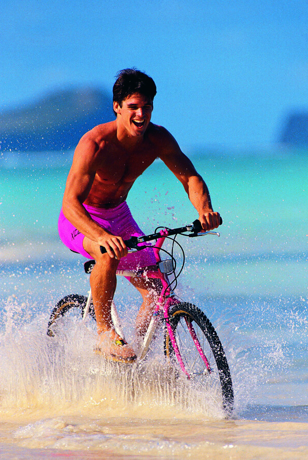 沙滩上骑自行车的男士图片